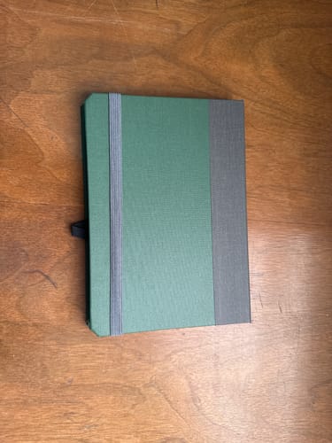 Customer's green and grey book-style iPad Mini Case closed on a wooden table.