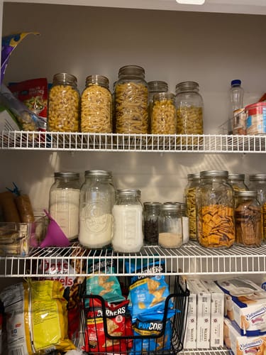Customer's pantry with shelves of mason jars filled with pasta and crackers, organized with the Mason Genie sealer kit.