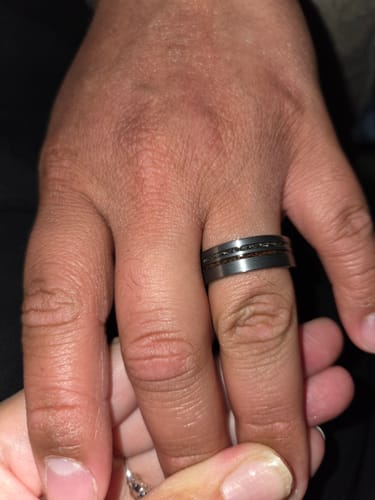Close-up of a customer wearing the elegant Comet ring, showing the dark band and detailed inlay.