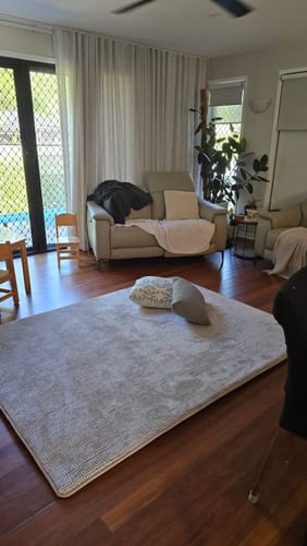 Customer's pebble weave Mellow Mat in a living room with dark wood floors and a beige couch in the background.