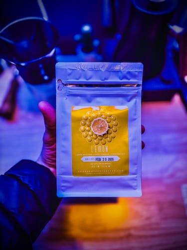 Reviewer holds a bag of Lemon Colombia Caturra coffee under moody, blue light.