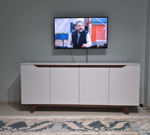 Yorumcunun odasına yerleştirdiği beyaz ve ceviz renkli Rani konsolu, duvara monte bir televizyonun altında duruyor.