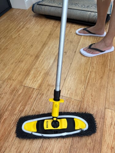 Reviewer's KoalaMop Cloth fitted onto a yellow mop head, demonstrating its compatibility on a wooden floor.