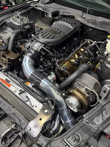 Customer's engine bay showing bronze Billet Coyote VCT Valve Covers installed with a turbocharger system.