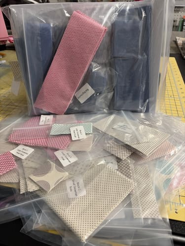 Customer shows the precut fabric pieces from the Tilda Happy Winter Snowman quilt kit, sorted into labeled bags.