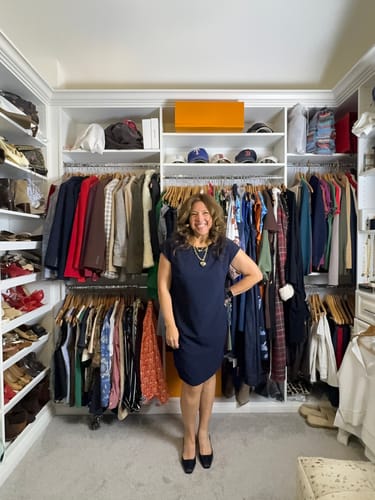 Reviewer smiling while wearing the dark navy Maaza Travel Dress in a walk-in closet.