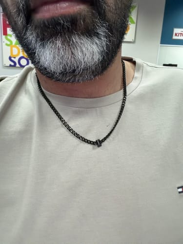 A close-up of a reviewer wearing the black Legacy necklace with a single bead against their t-shirt.