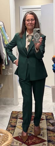 Reviewer taking a full-length mirror selfie wearing the green Colby Travel Pants styled with a matching blazer.