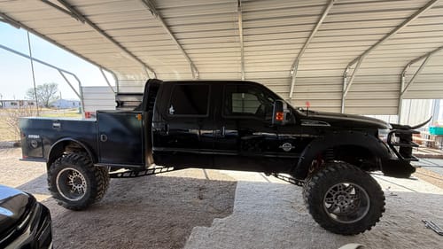 Customer's black Ford Super Duty truck with a Shackle Flip Kit installed, showing a significant 4-inch lift under a carport.