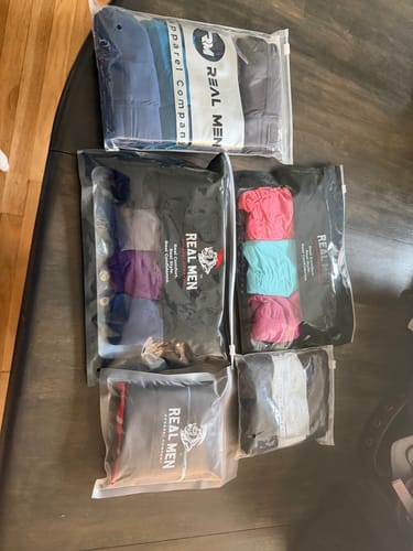 Customer's collection of several new packages of Nylon Mesh Bikini Briefs laid out on a dark surface.