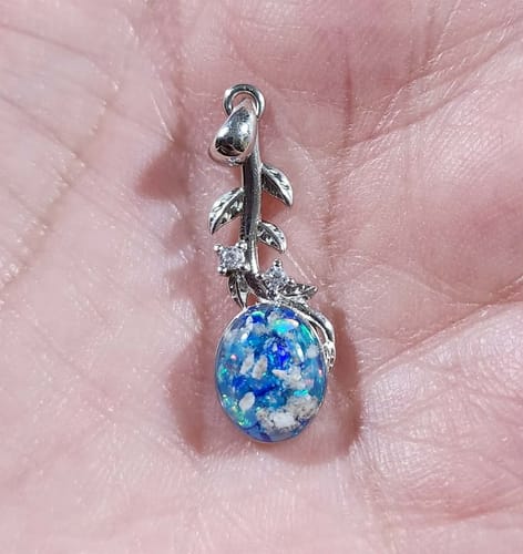 A reviewer holds the Leaf Drop Pendant in their palm, showing the blue and white ash-infused stone.