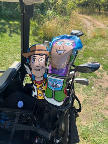 Customer's Woody and Buzz Lightyear fairway headcovers side-by-side in a golf bag on a cart.