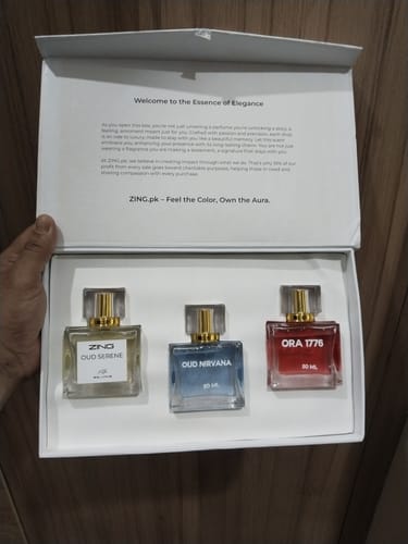 A reviewer holds the open presentation box for the OUD Supreme BUNDLE, showing the three fragrance bottles inside.