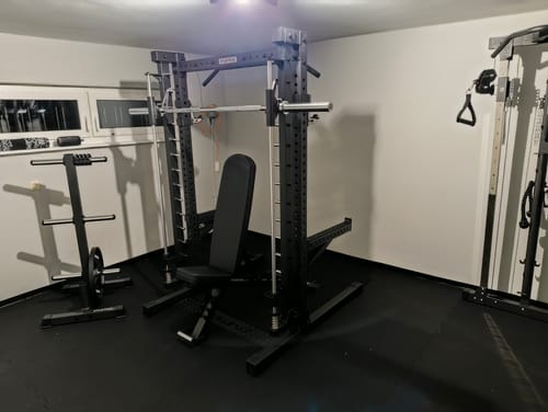 Kunde zeigt das R7_Smith_Option_200_Paket1 in einem Heim-Fitnessstudio mit einer Hantelbank.
