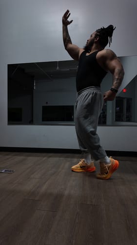 Reviewer in a gym posing to show the form-fitting style of the black Premium Ultra-Soft Cotton Fitted Tank.