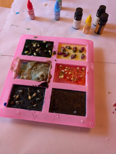 Reviewer's homemade soaps from the craft subscription box setting in a pink mold with colorful botanicals.