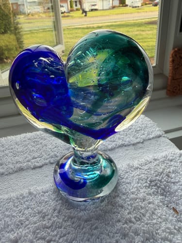 Reviewer's blue and teal Glass Heart with Cremains catching the light on a windowsill.