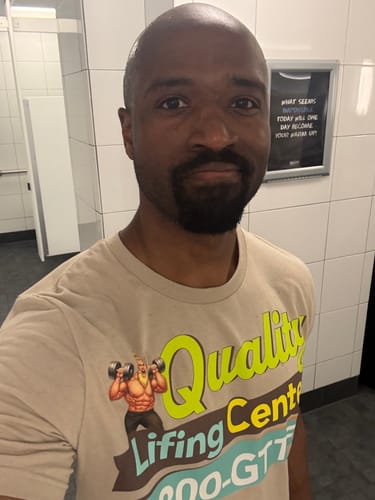Customer taking a selfie while wearing the tan Quality Lifing Center T-Shirt.