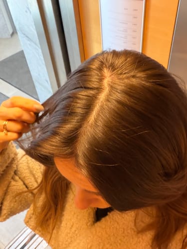 Close-up of a reviewer's parted dark brown hair, showing the results of the Grey Cover product.