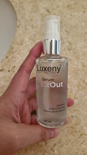 Cliente sosteniendo en la mano el frasco transparente del Serum Antifrizz.