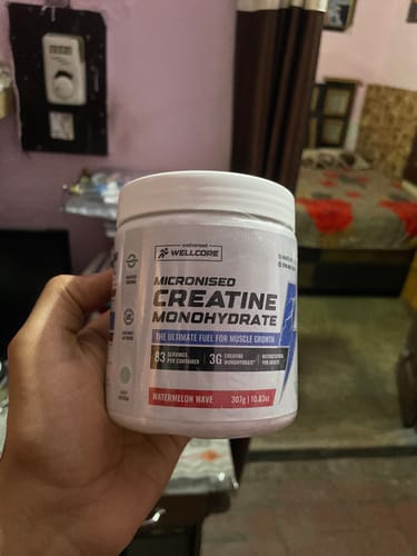 Customer holding a white tub of Wellcore Micronised Creatine Monohydrate in the Watermelon Wave flavor.
