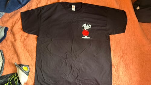 Customer's black summer t-shirt with a small cartoon graphic on the chest, laid out flat.