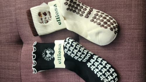 Reviewer's two pairs of cute sticky socks: a cream 'Barre & Espresso' pair and a black 'Pilates Social Club' pair.
