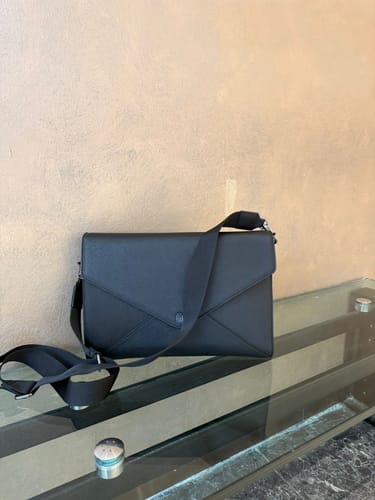 Customer's elegant black Executive Workpod bag with its strap, sitting on a glass console table.