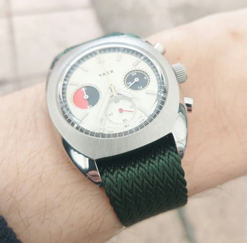 Close-up of a reviewer's watch on their wrist, showcasing the woven texture of the hunter green SharkFin strap.