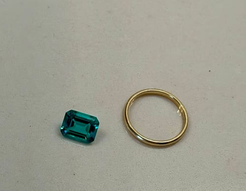 Customer's Doveggs 4ct Columbia emerald loose stone shown next to a gold ring for size comparison.