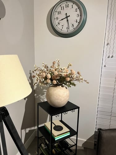 Recensents Wax Arrangement - Crème in een bolle, crèmekleurige vaas op een zwart bijzettafeltje in een hoek van de kamer.