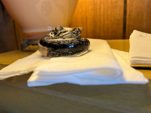 Reviewer's custom glass cat sculpture with dark swirls shown from the side on a wooden surface.