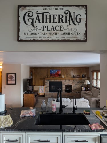 Customer's framed Gathering Place Personalized Sign hanging on the wall in a kitchen above a pass-through.