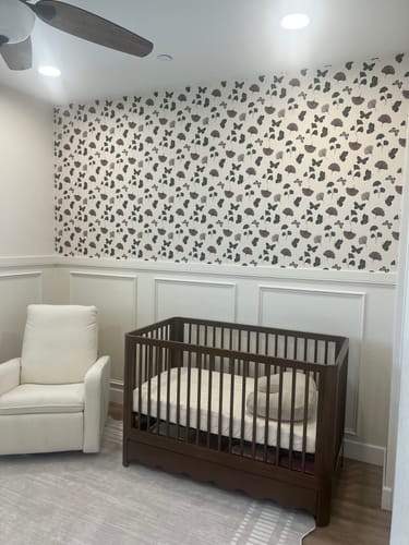 Reviewer's Jovie Wallpaper with a butterfly and flower pattern shown on an accent wall in a nursery.