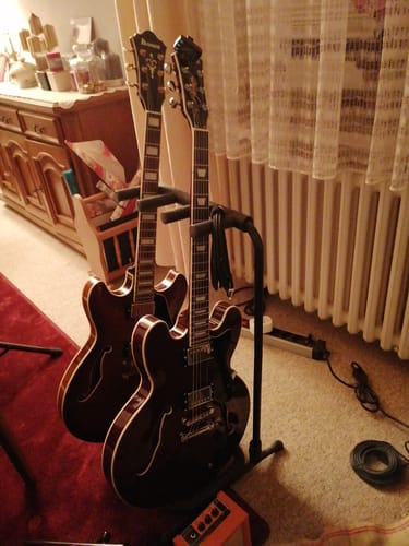 Die Donner DJP-1000 Jazz E-Gitarre eines Rezensenten steht neben einer zweiten Gitarre auf Ständern in einem Raum.