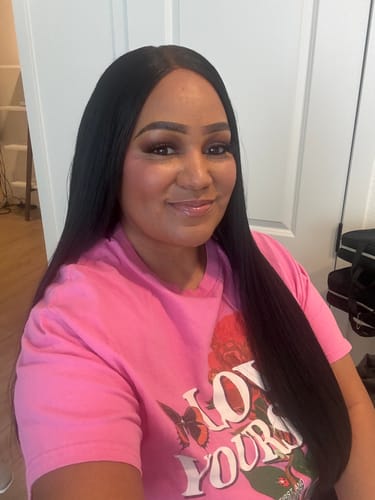 Reviewer shows the natural-looking, shiny APIA wig, styled long and straight with a center part.