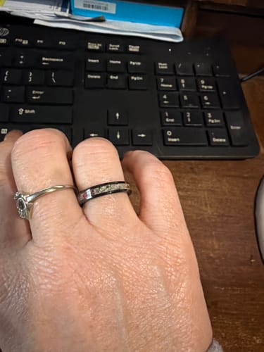 Customer's hand wearing the black titanium carbide cremation ring with a red and white speckled inlay.