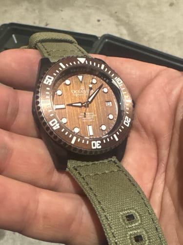 Close-up of a customer's Oceaneva Deep Marine Explorer III watch with an aged bronze dial and green canvas strap.