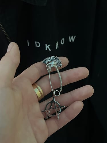 Reviewer holding the PUNK SAFETY PIN in their palm, showing it with an anarchy pendant they have added.