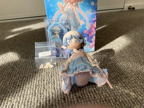 Reviewer's Antu Tidal Mermaid action figure sitting on a carpet with its box, showing it cannot stand on its own.