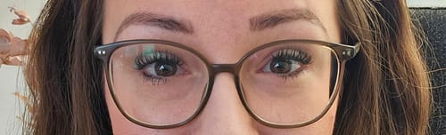 Nahaufnahme einer Kundin, die die Wimpern aus dem CAFE GLAM STARTER KIT hinter ihrer Brille trägt.