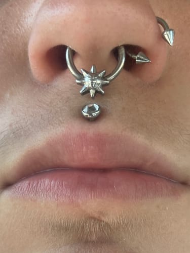 Close-up of a customer wearing the silver SUNNY SEPTUM, which features a spiky sun design.