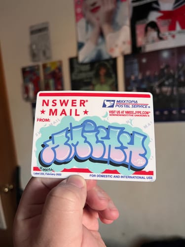 Reviewer holding a custom vinyl sticker designed like a mailing label with colorful graffiti art in the center.