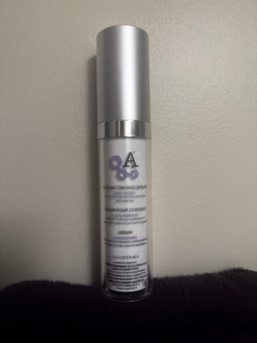 Reviewer's bottle of Alastin Skin Nectar Face Serum standing on a dark surface.