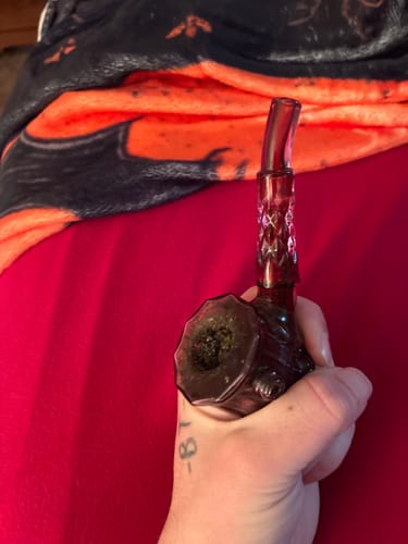 Reviewer holding the dark red NWTN Home Highball Glass Pipe, showing its ornate design and how it fits in their hand.