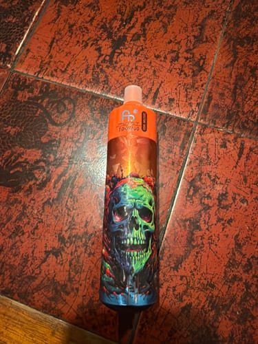 Customer's RandM Tornado disposable vape bar with a colorful skull design, standing on a tiled floor.