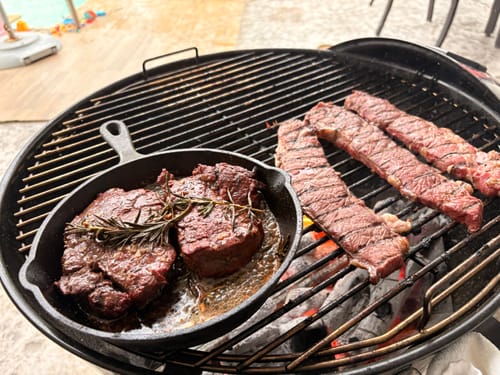 Cliente cocinando filetes cabrería en una parrilla redonda, algunos en un sartén de hierro y otros en la rejilla.