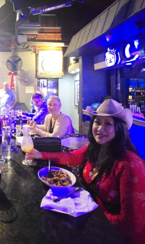 Reviewer smiling at a bar while wearing the red lace crochet jumpsuit.