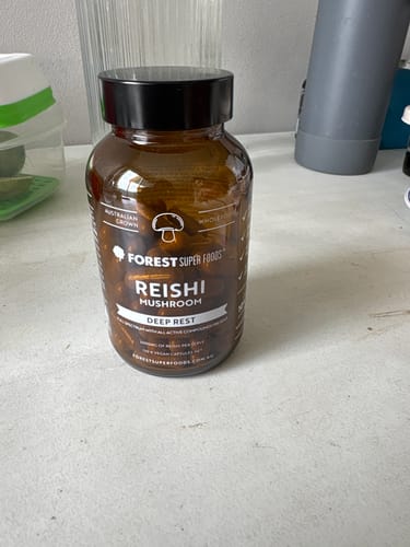 Customer's bottle of Forest Super Foods Reishi Mushroom capsules sitting on a light-colored table.