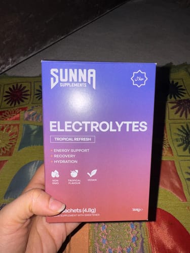 Reviewer holds the purple and pink box of Electrolytes - Tropical Refresh.